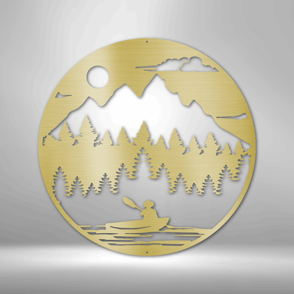 Circular gold-colored metal cutout depicting a mountain landscape with trees and a person in a canoe.