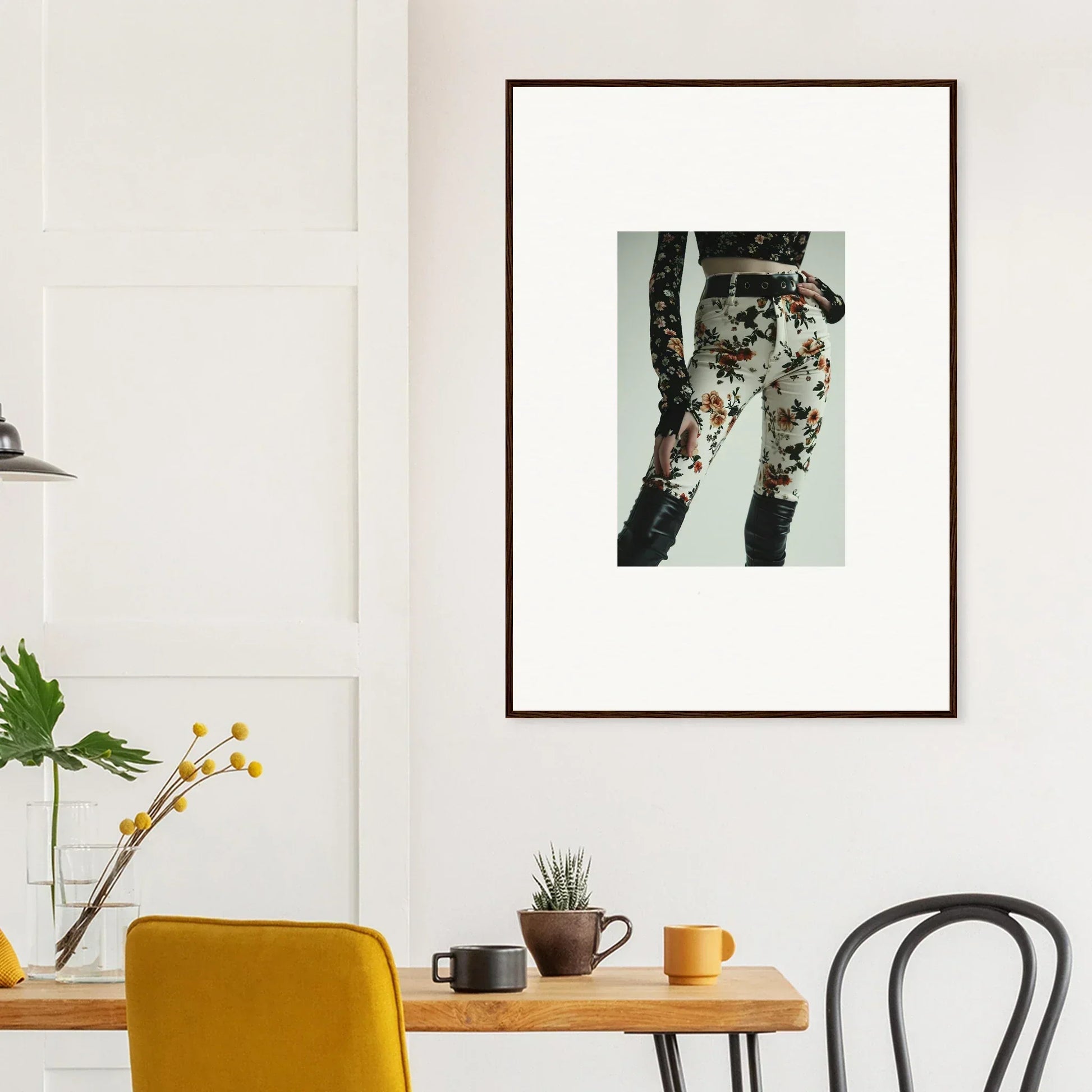 Framed artwork depicting a person’s legs wearing floral-patterned pants.