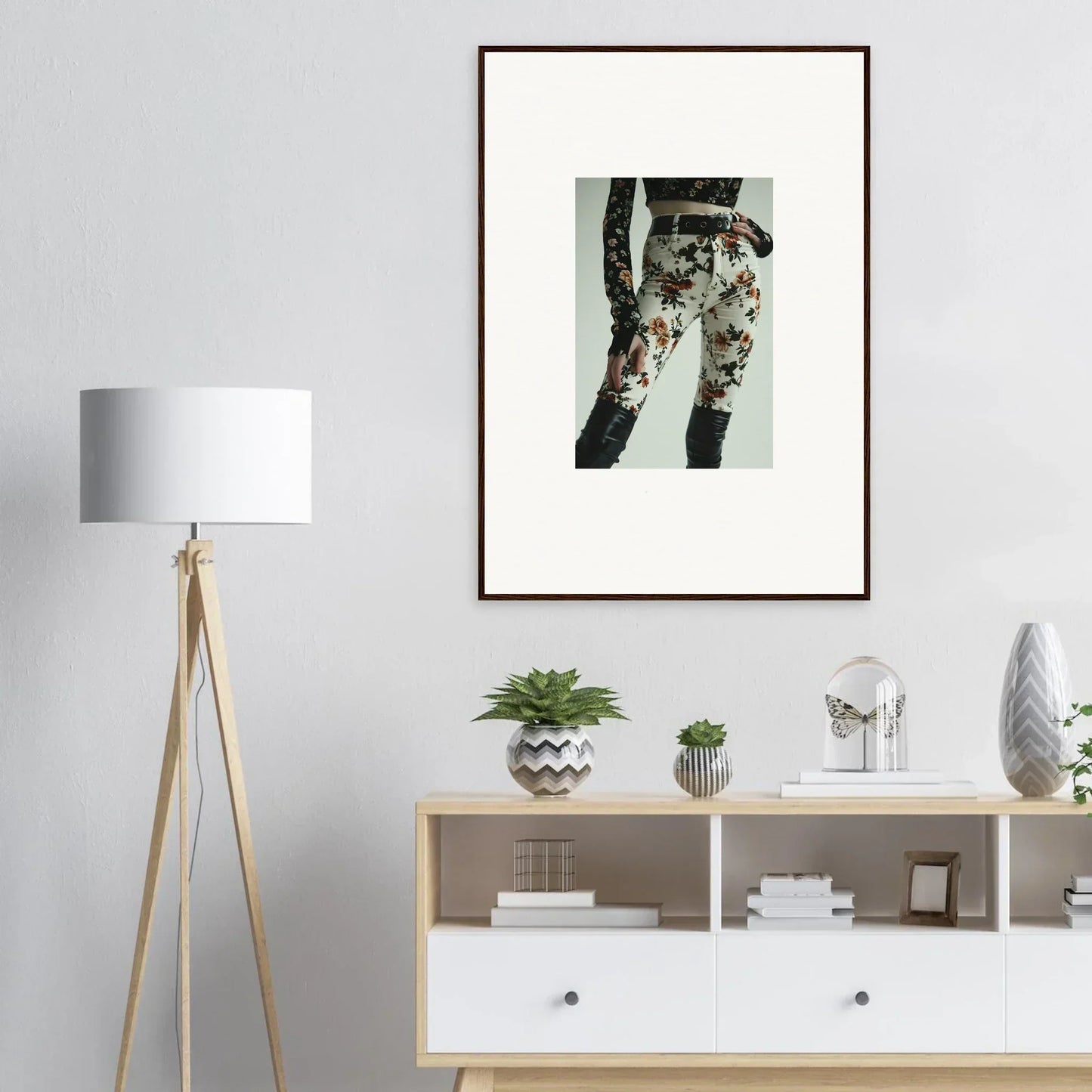 Framed artwork showing a person’s legs wearing floral patterned pants.