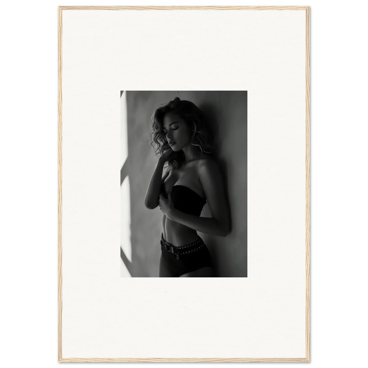 Black and white photograph of a woman in lingerie posing against a wall.