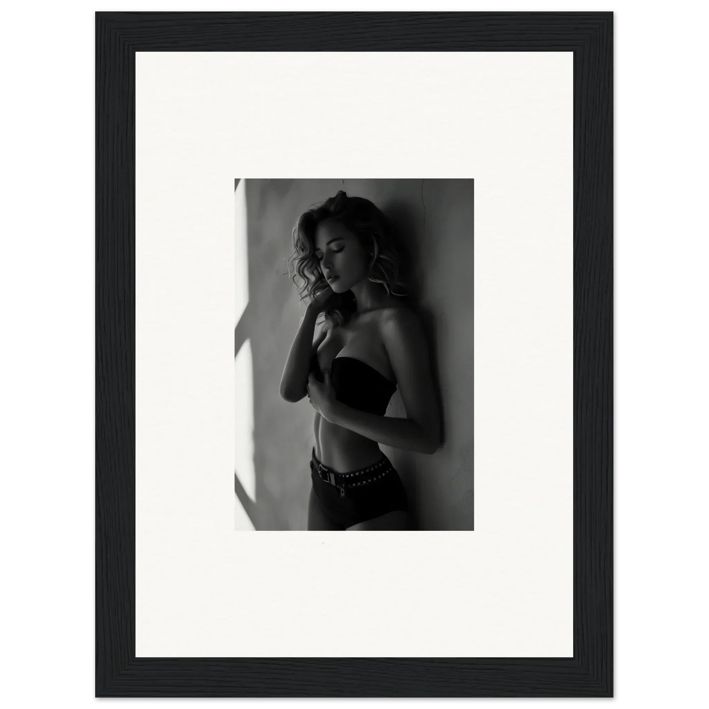 Black and white photograph of a woman in a strapless top, framed in a simple black frame with white matting.