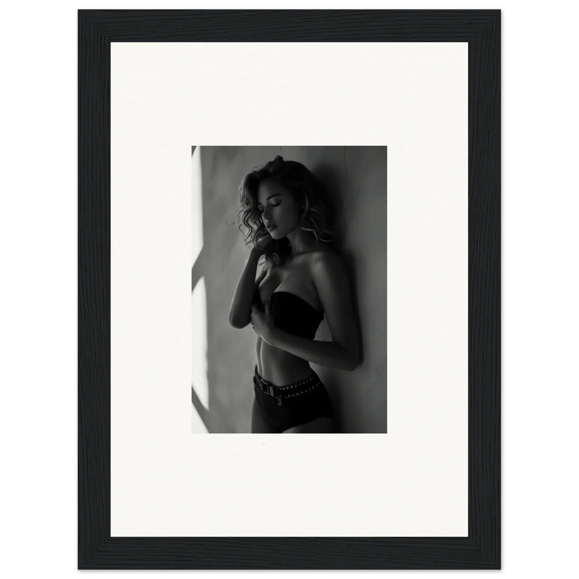 Black and white photograph of a woman in a strapless top, framed in a simple black frame with white matting.