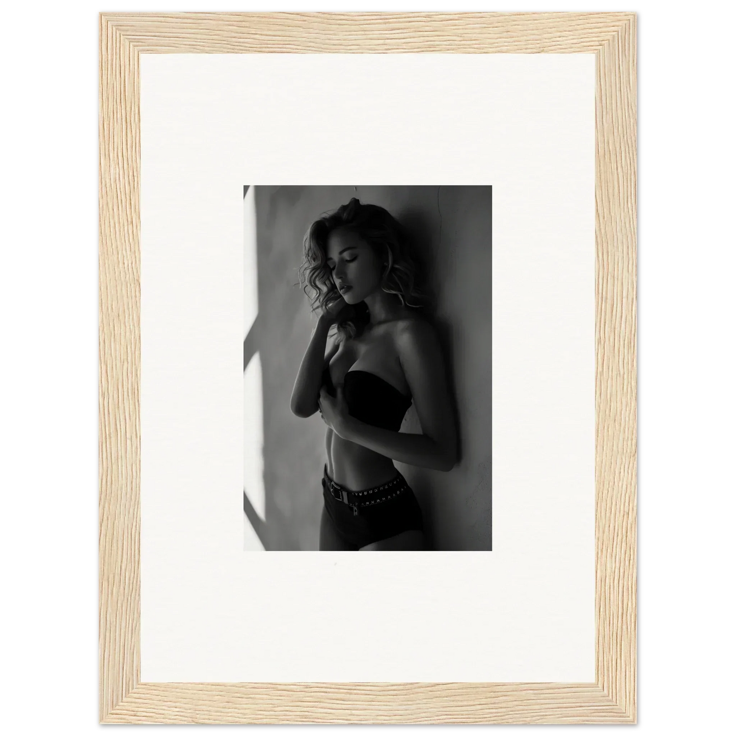 Framed black and white photograph of a woman in lingerie posing against a wall.