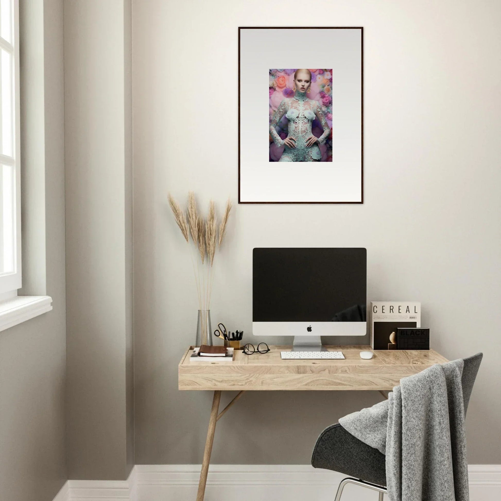 Minimalist home office workspace with a wooden desk, computer, and framed artwork.