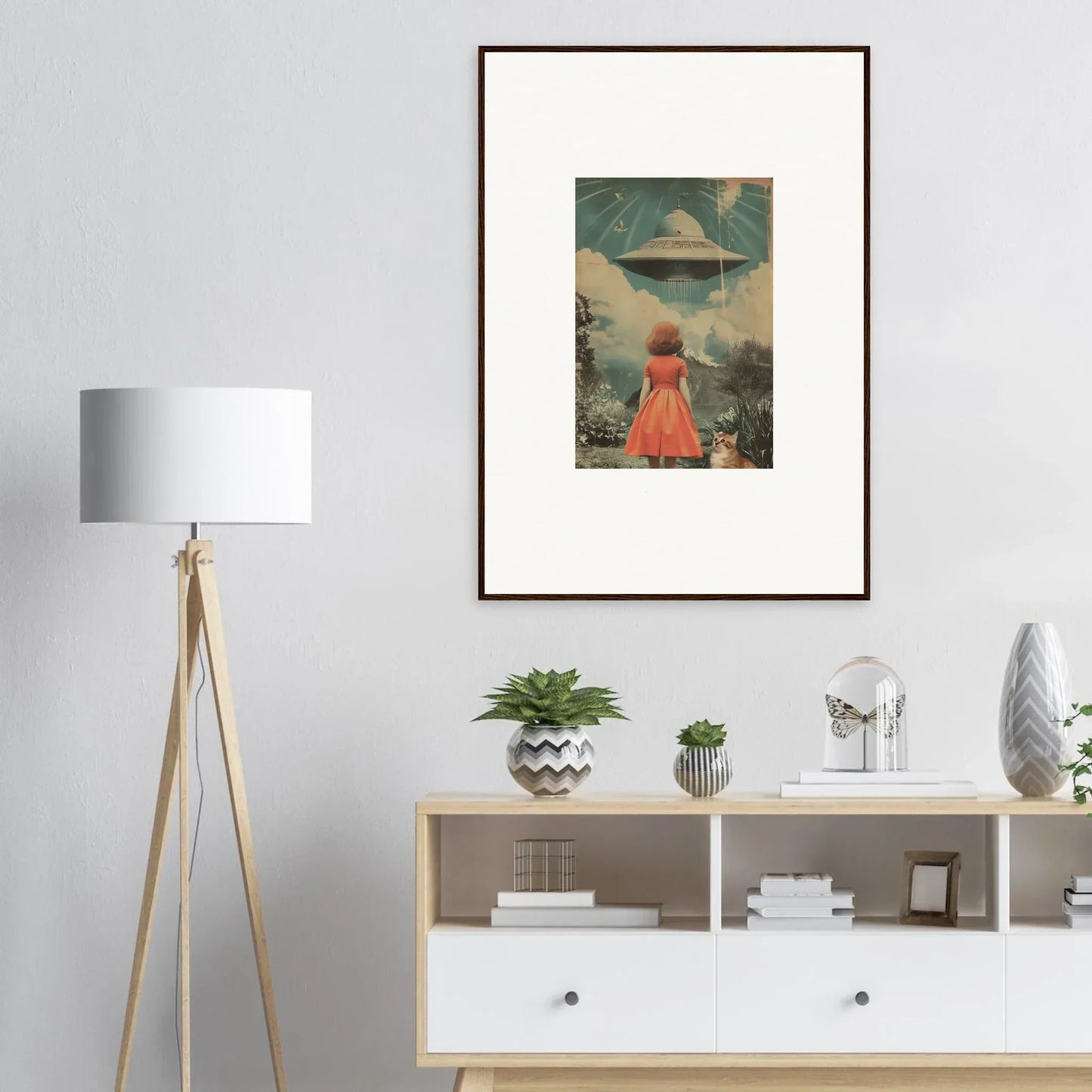 Framed wall art of a person in a red dress facing a UFO in surreal landscape