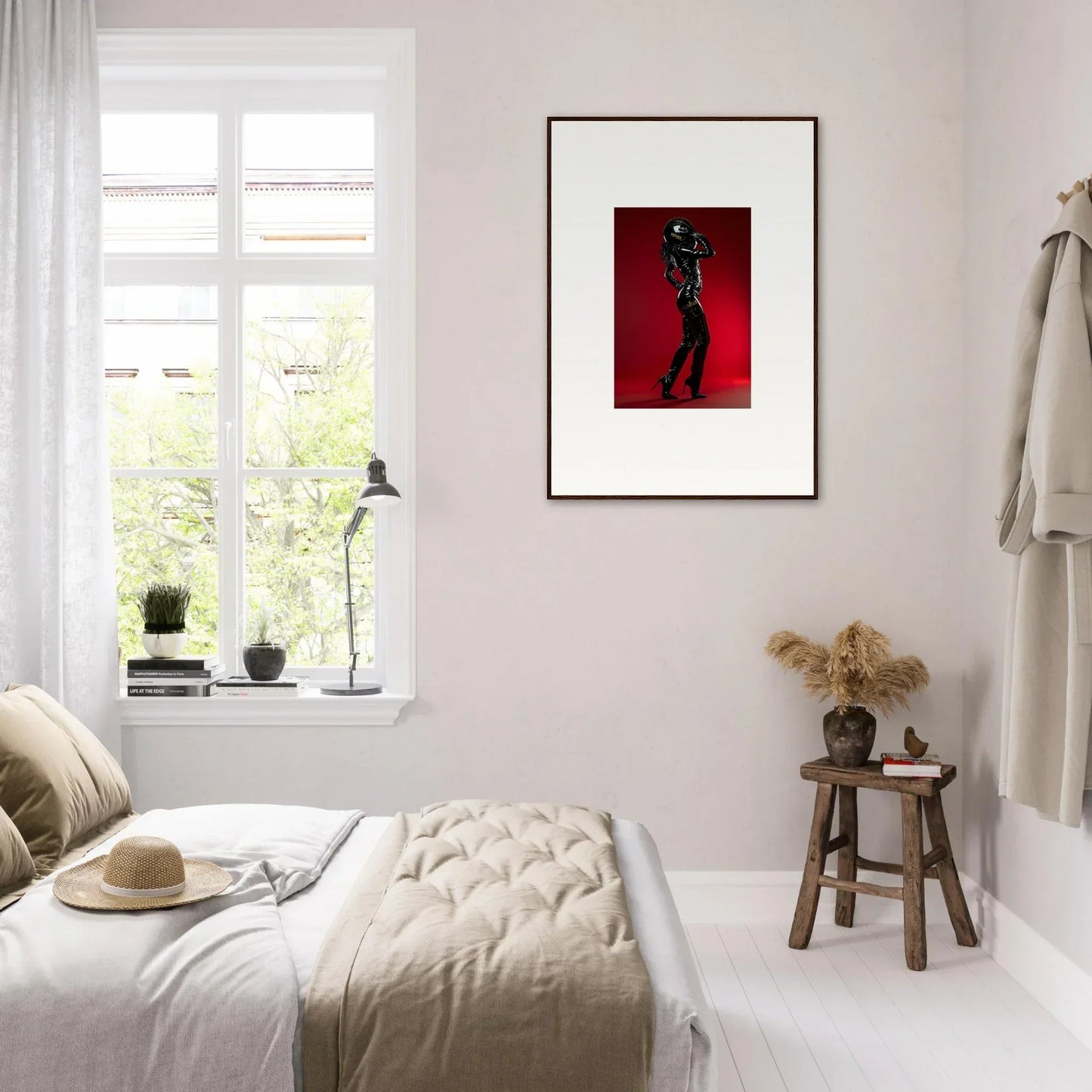 Framed artwork featuring a figure on a red background hanging on a white wall.