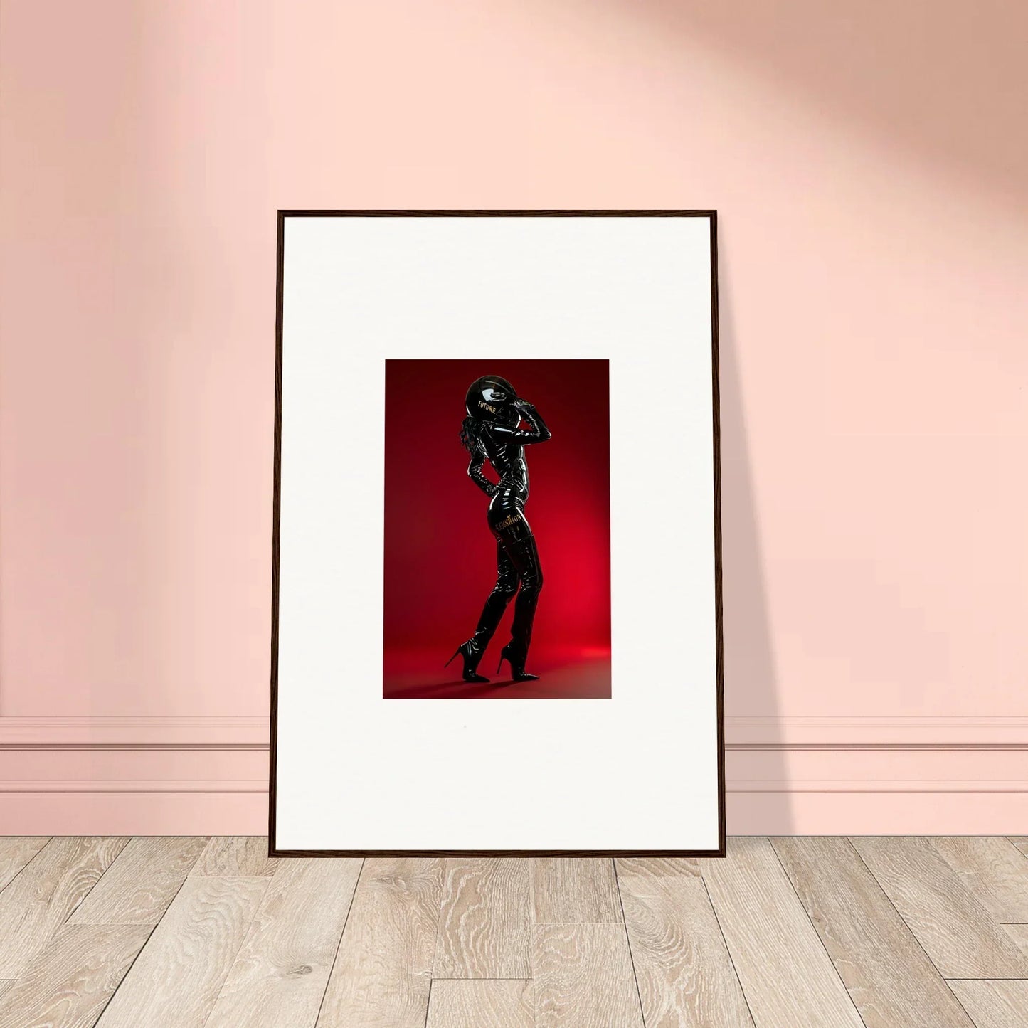Framed photograph of a figure in a shiny black outfit striking a dynamic pose against a red background.