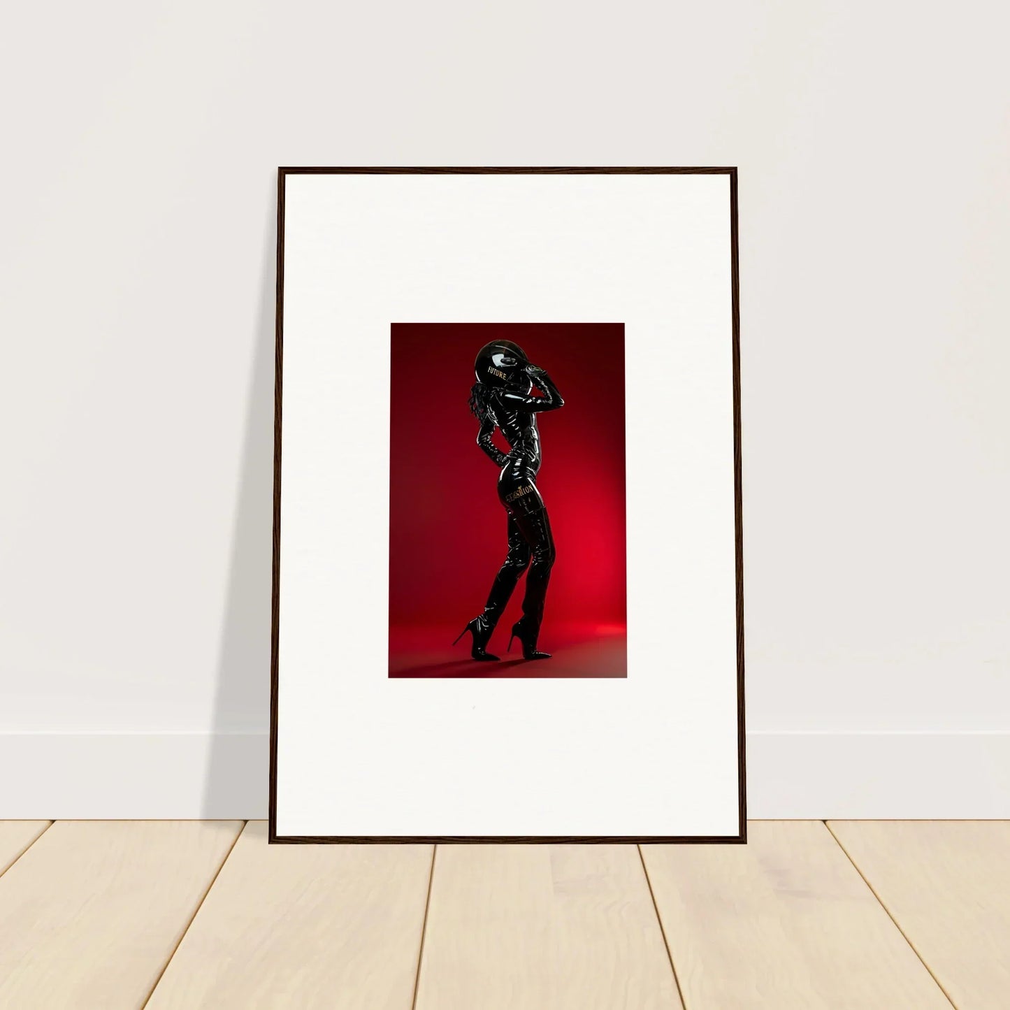 Framed photograph of a silhouetted figure holding a helmet against a red background.