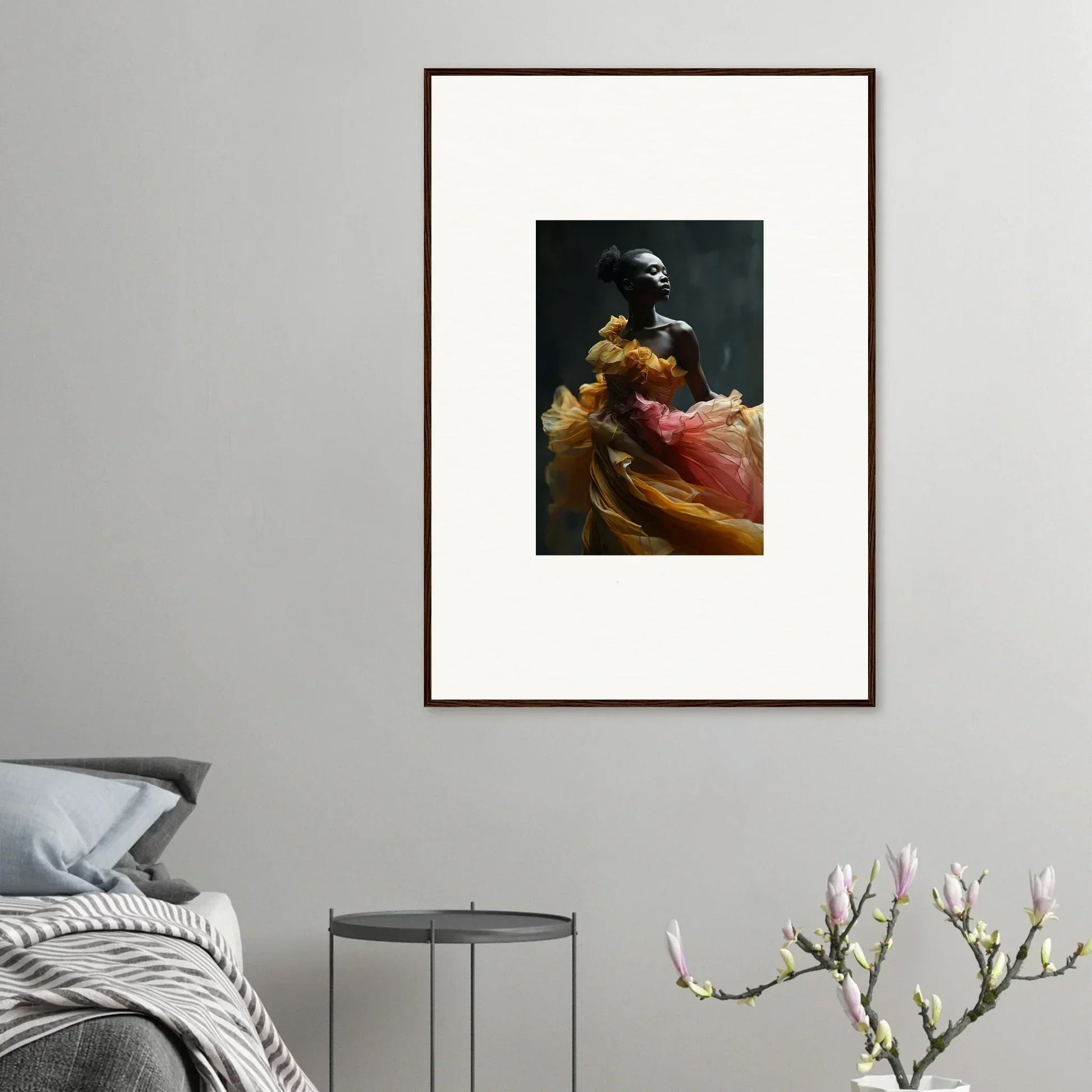 Framed artwork featuring a figure in vibrant yellow and red fabric against a dark background.