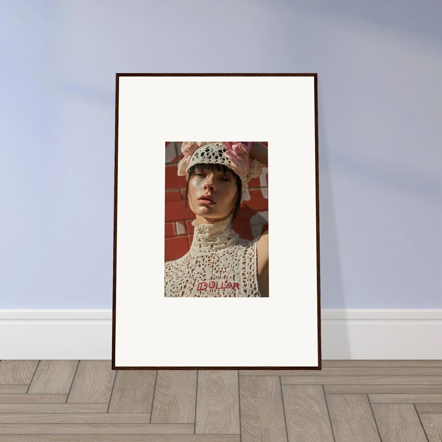 Framed portrait photograph of a person wearing a white knit hat and high-necked top.