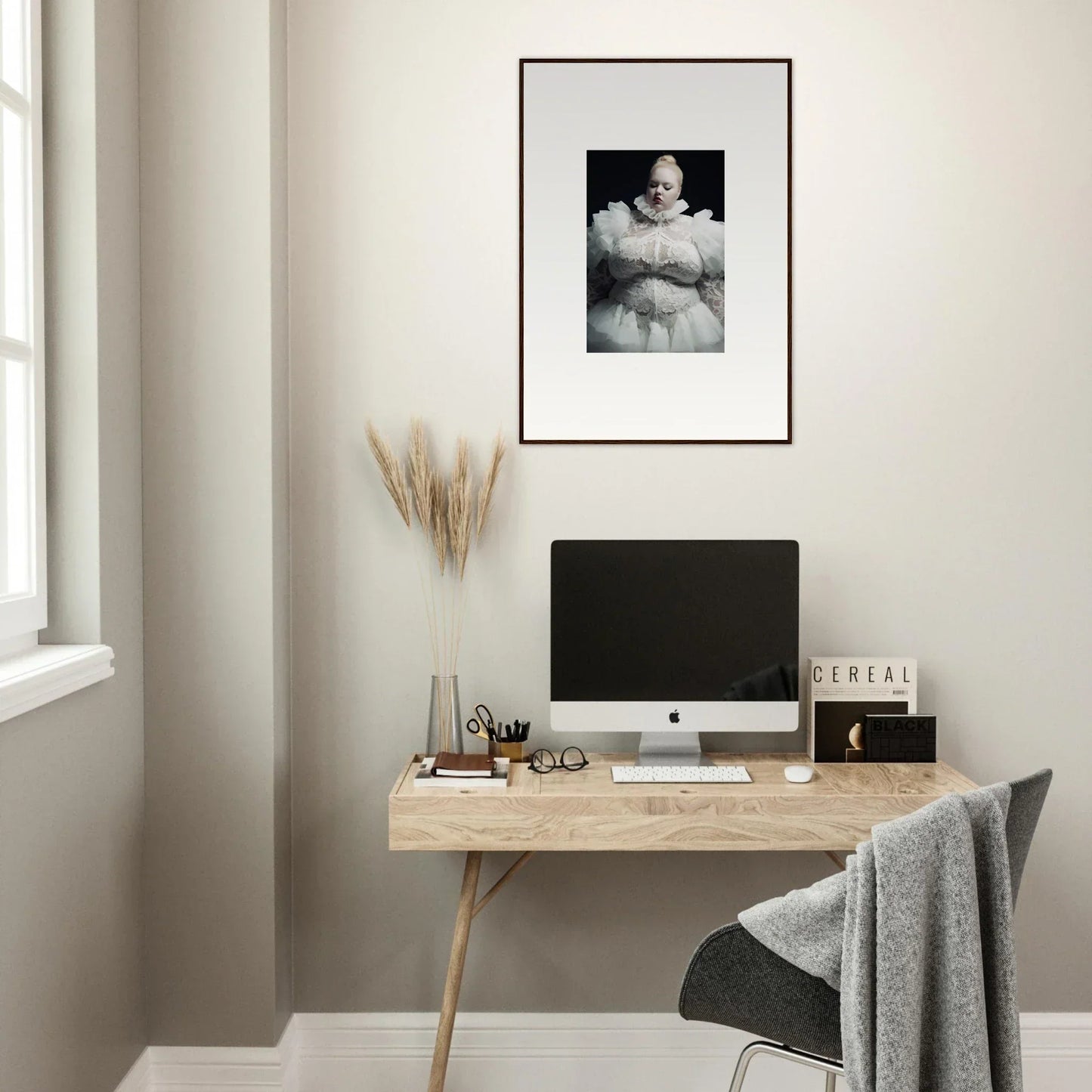 Minimalist wooden desk with a computer monitor and framed artwork above.