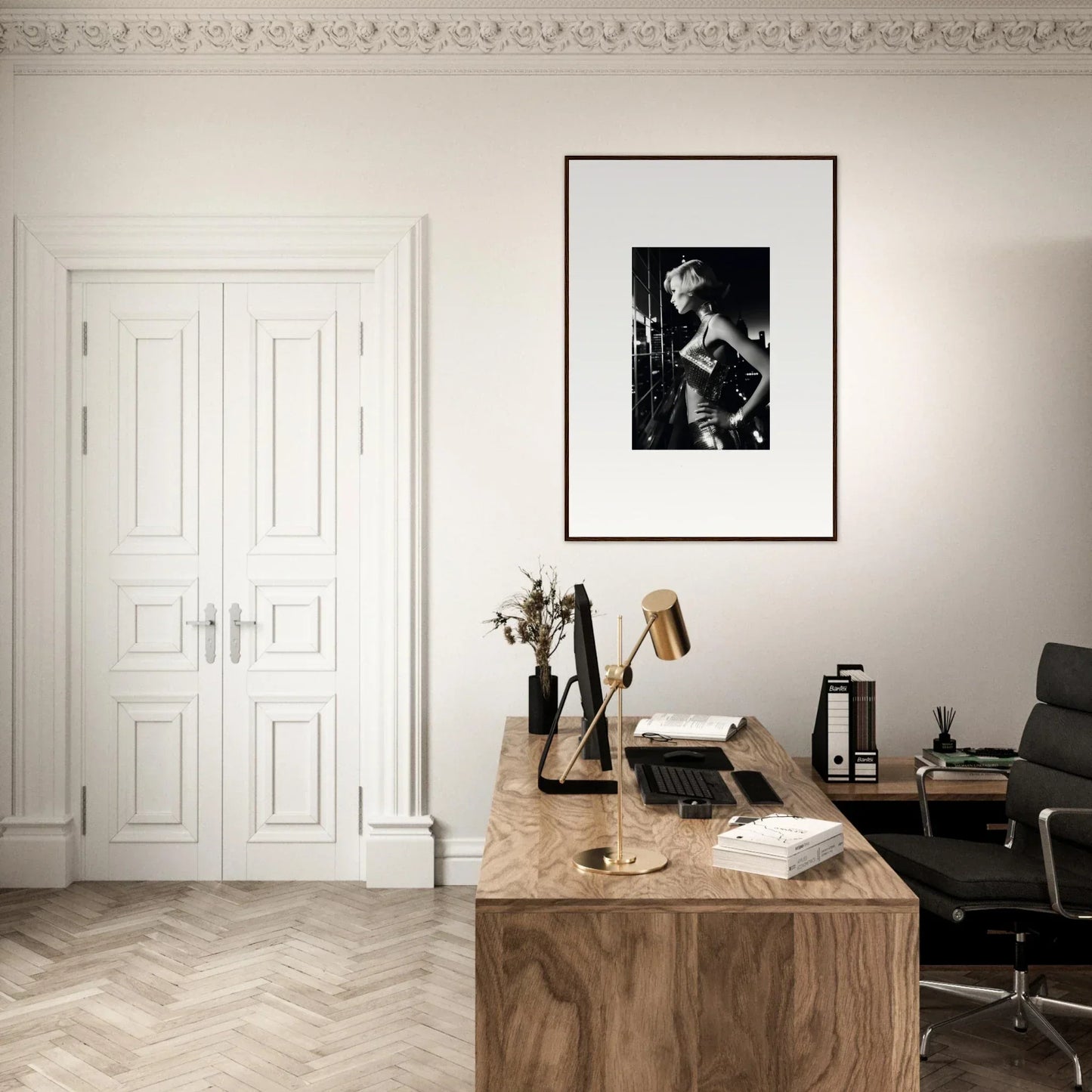 Wooden desk with various office items and a framed black-and-white photograph on the wall above it.
