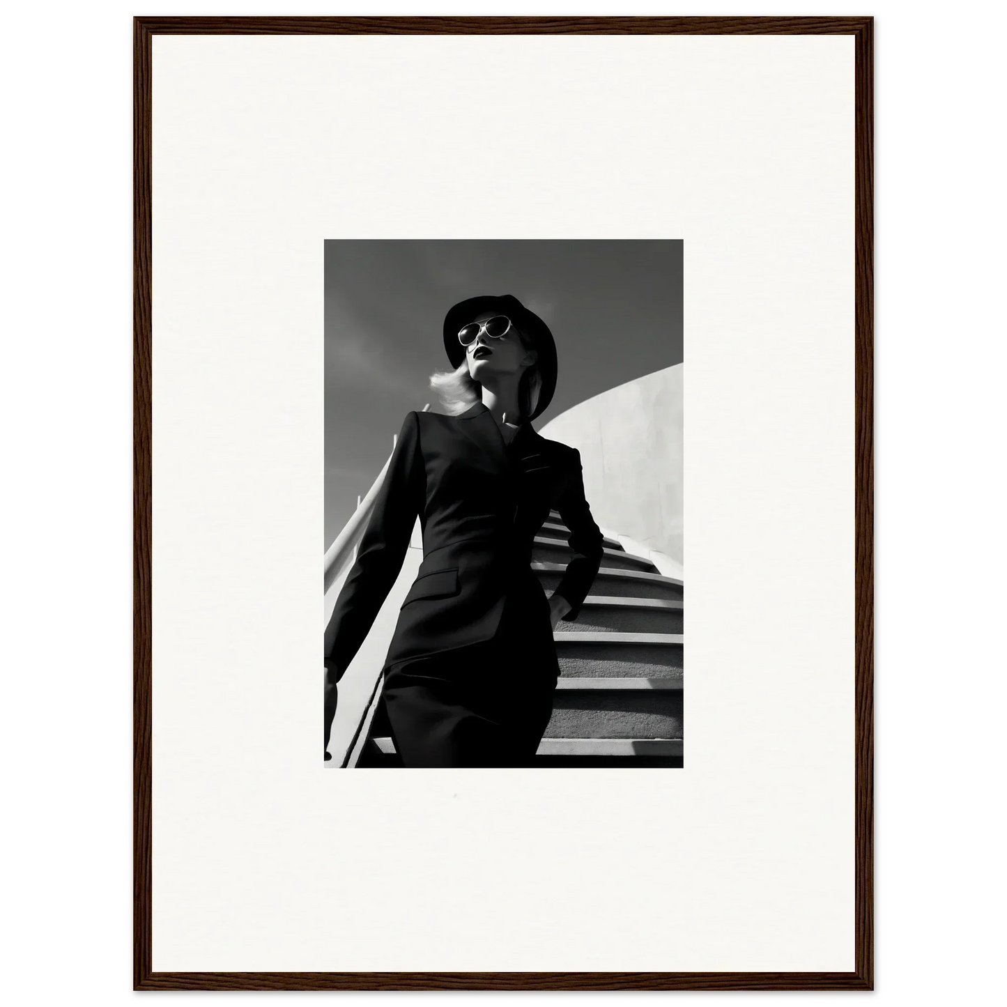 Black and white photograph of a stylishly dressed woman in a dramatic pose on stairs.