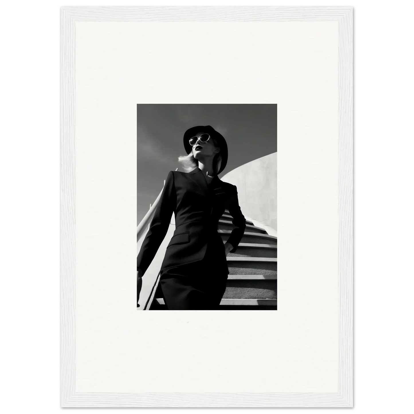 Black and white photograph of a person in a suit and hat standing on stairs.