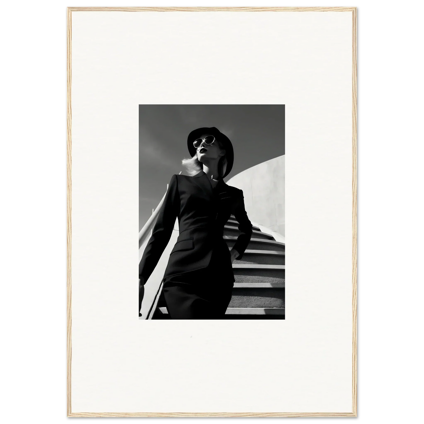 Black and white photograph of a person in a suit and hat ascending stairs.