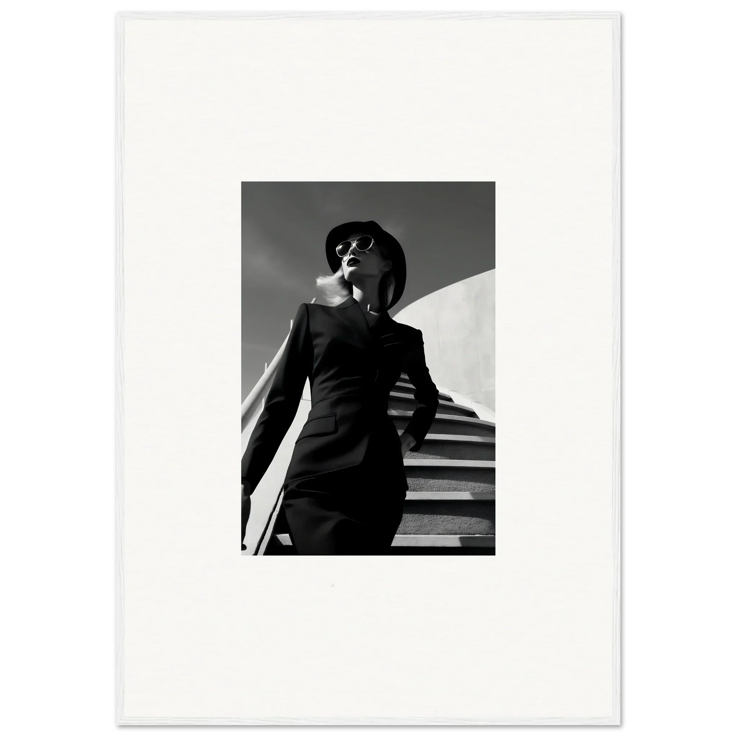 Black and white photograph of a person in a suit and hat standing on stairs.