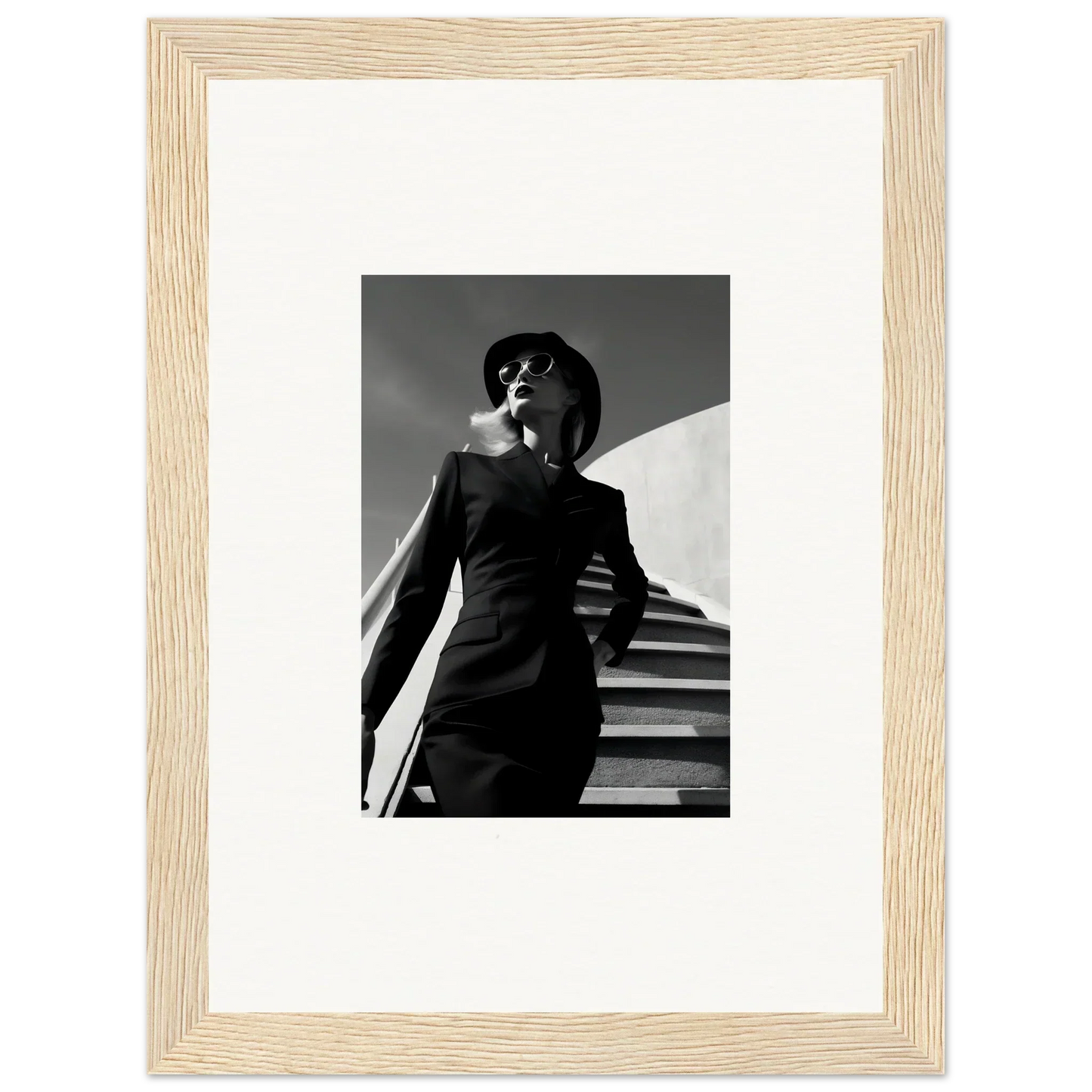 Black and white photograph of a person in a suit and hat standing on stairs.