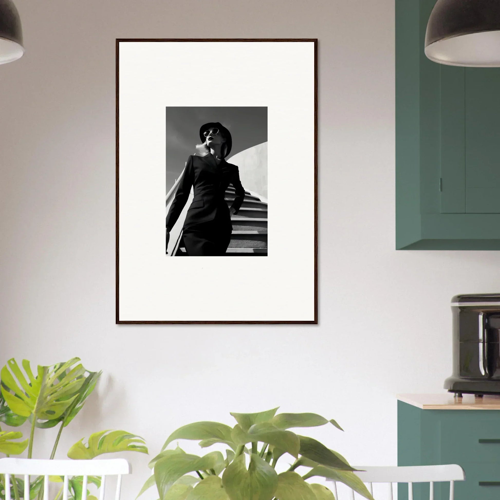 Framed black and white photograph of a person in a dark outfit standing on stairs.