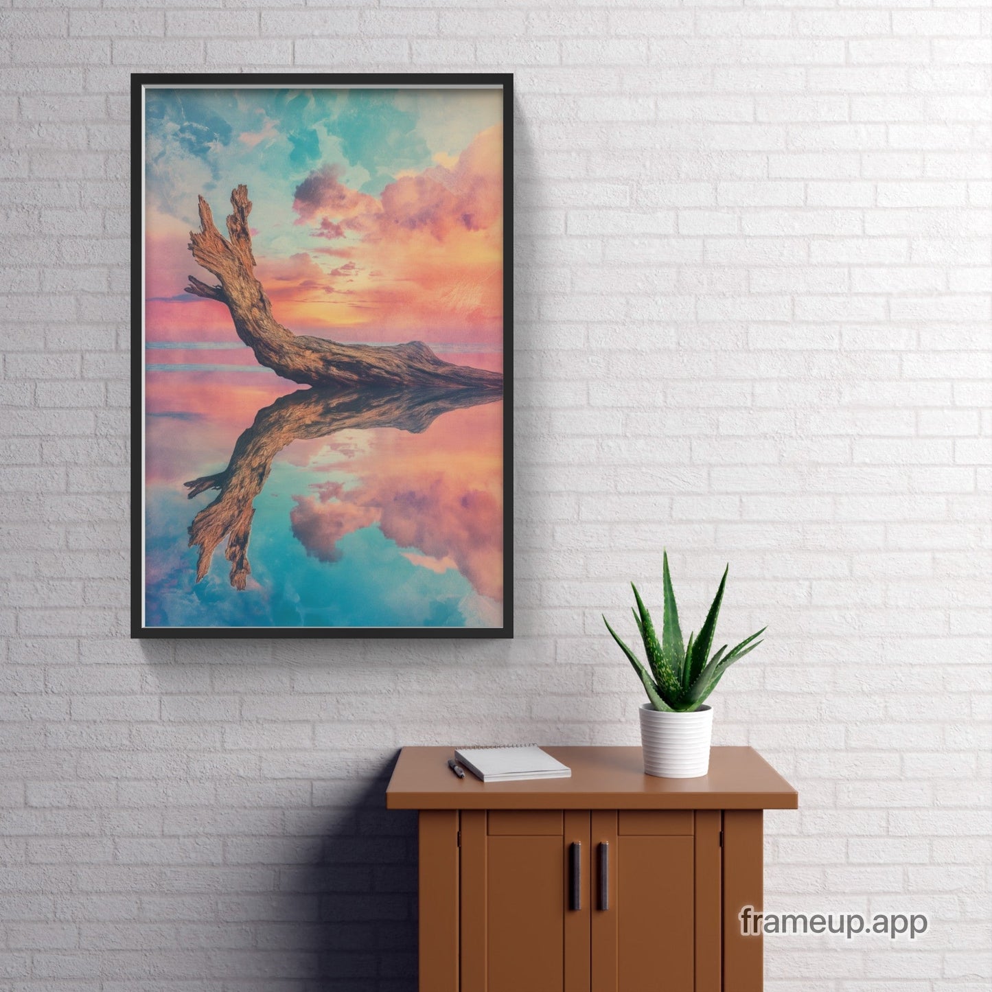 A framed print of a tree branch with a colorful sky in the background