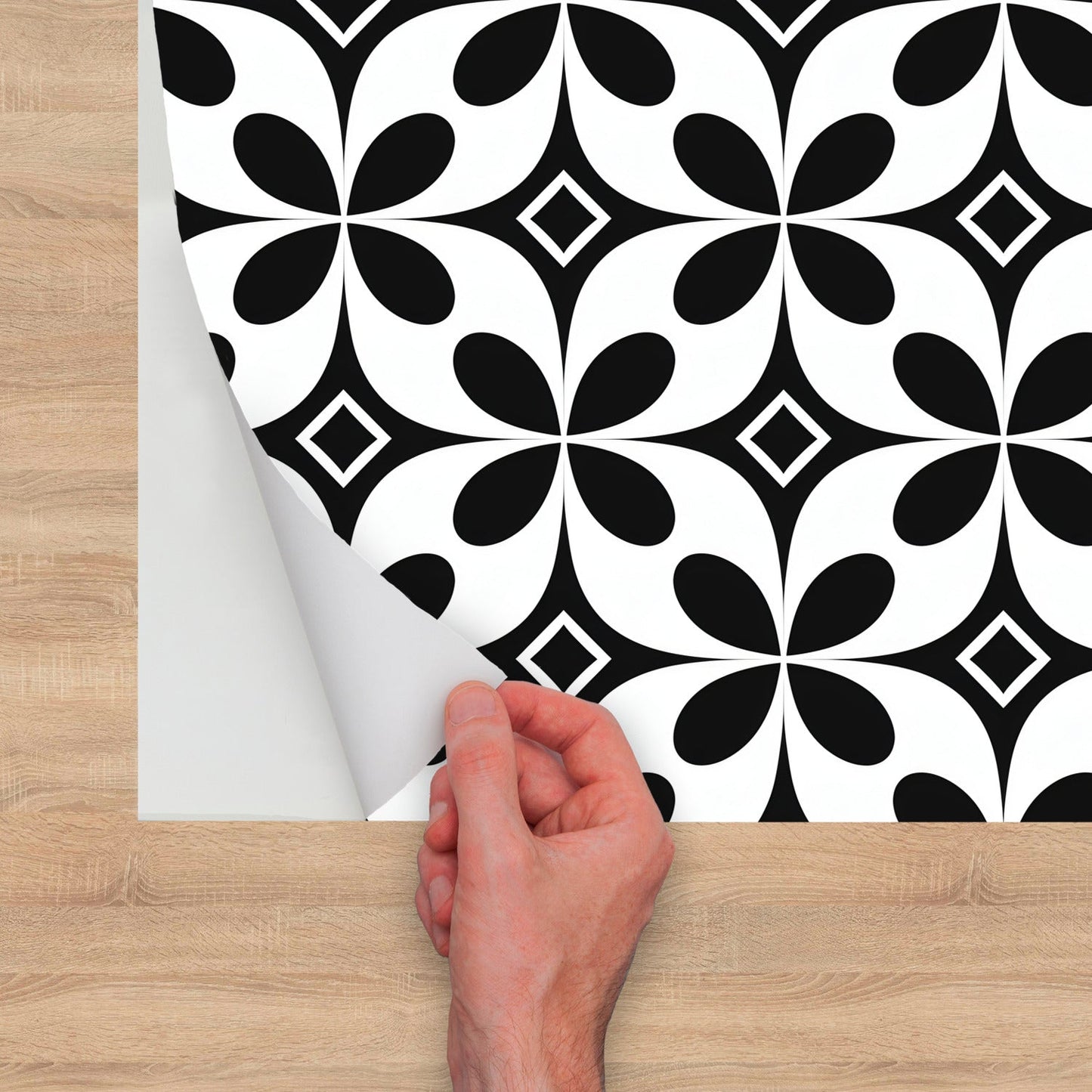 A hand is holding a piece of paper with a black and white pattern