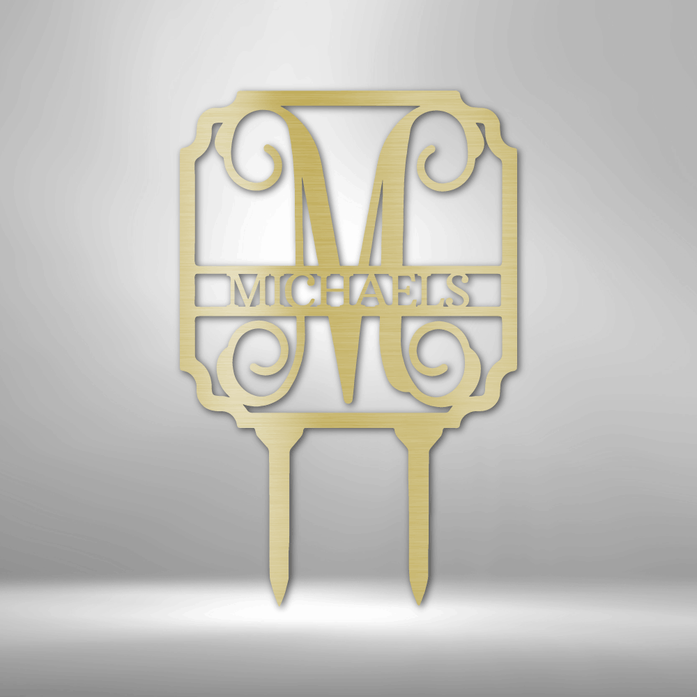 Gold-colored monogram cake topper featuring the letter ’M’ and the name ’MICHAELS’ in an ornate design with scrollwork.