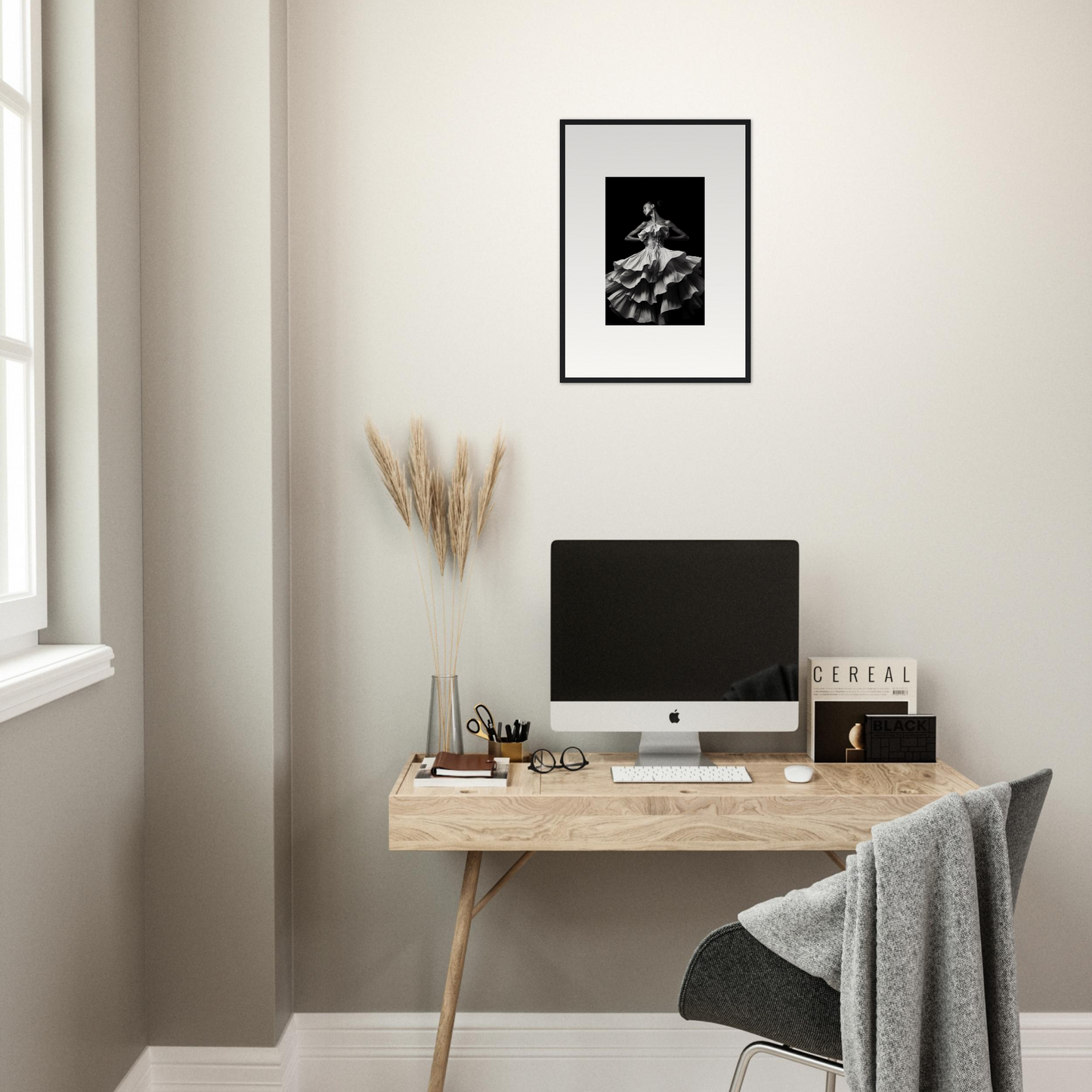 Minimalist home office workspace with a wooden desk, computer, and framed artwork.