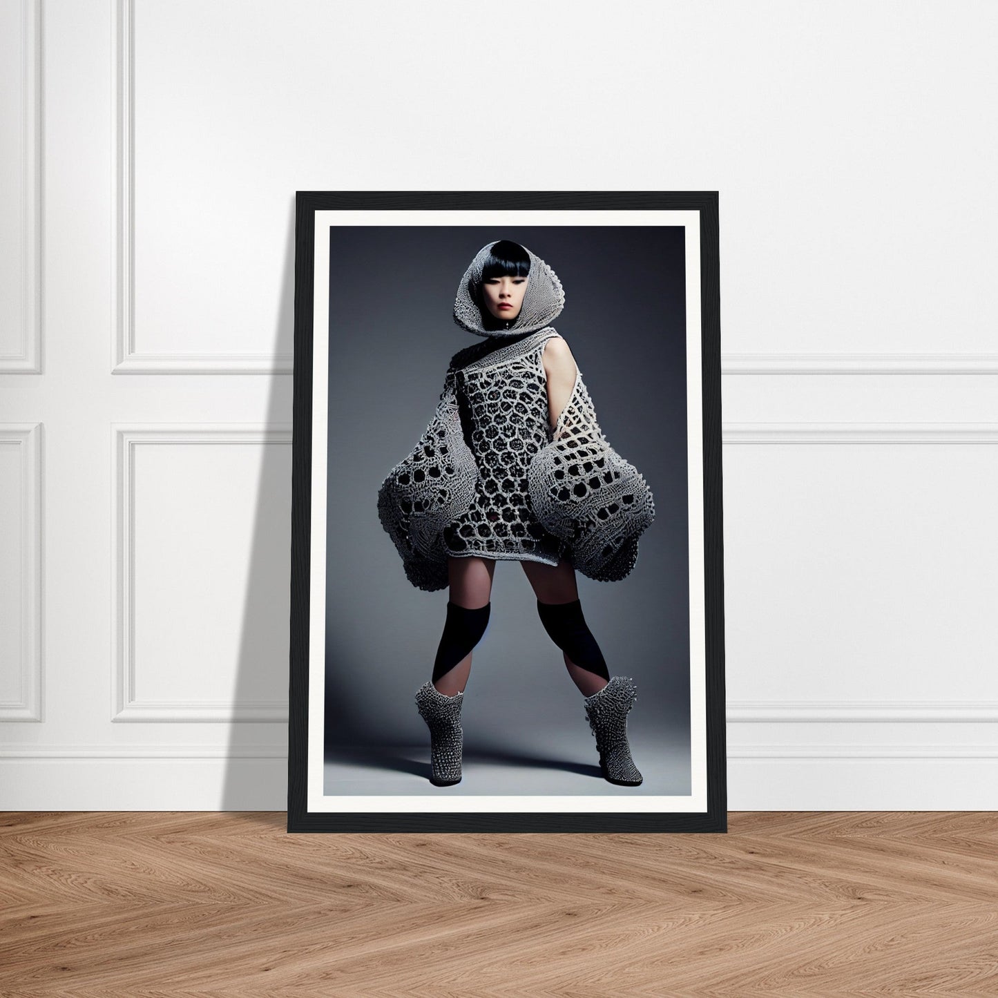 Framed photograph of a person wearing an avant-garde, oversized knitted garment with geometric patterns.