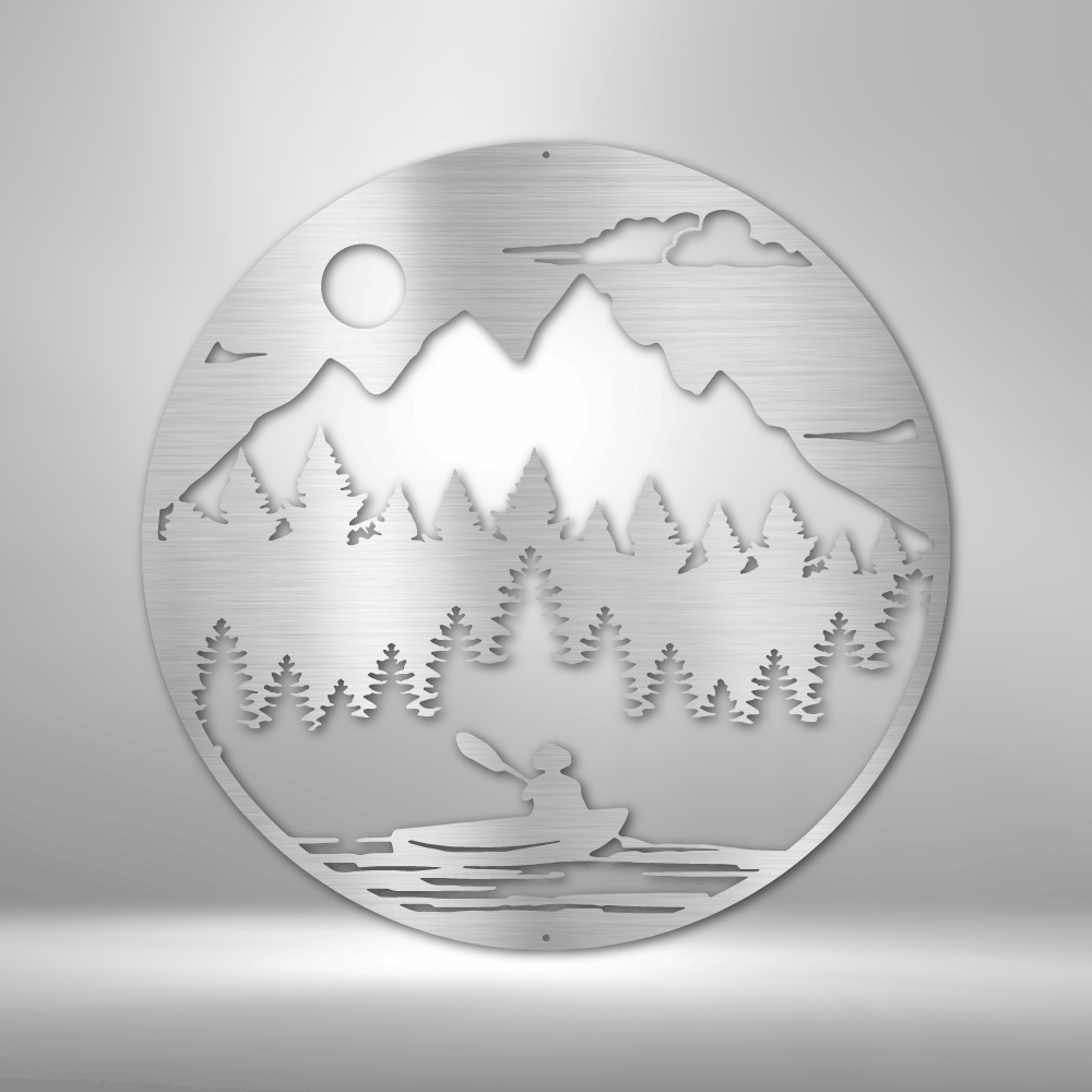 Circular metal wall art depicting a mountain landscape with trees and a kayaker.