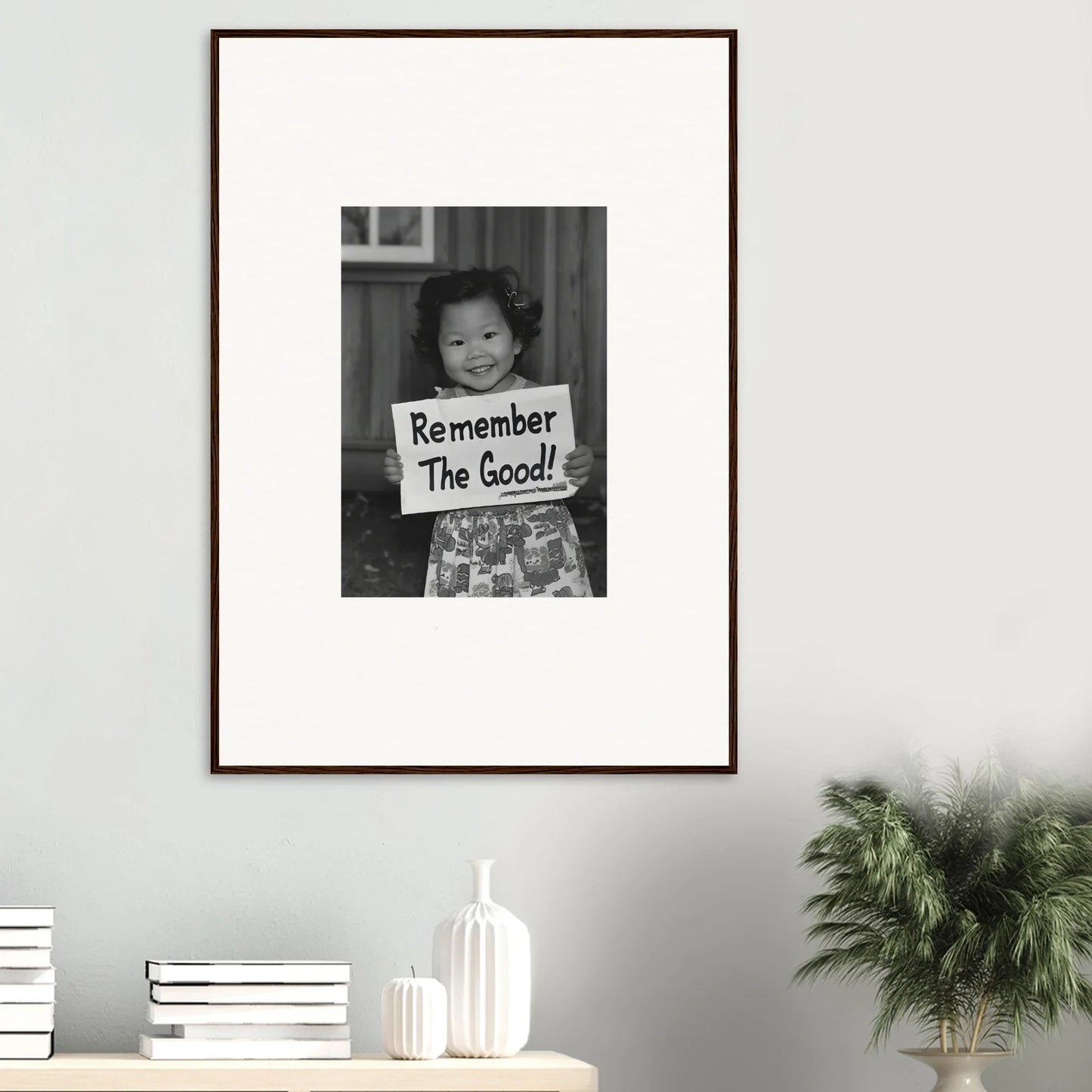 Framed black and white photo of a child with a sign for Essence Savor Whispers art