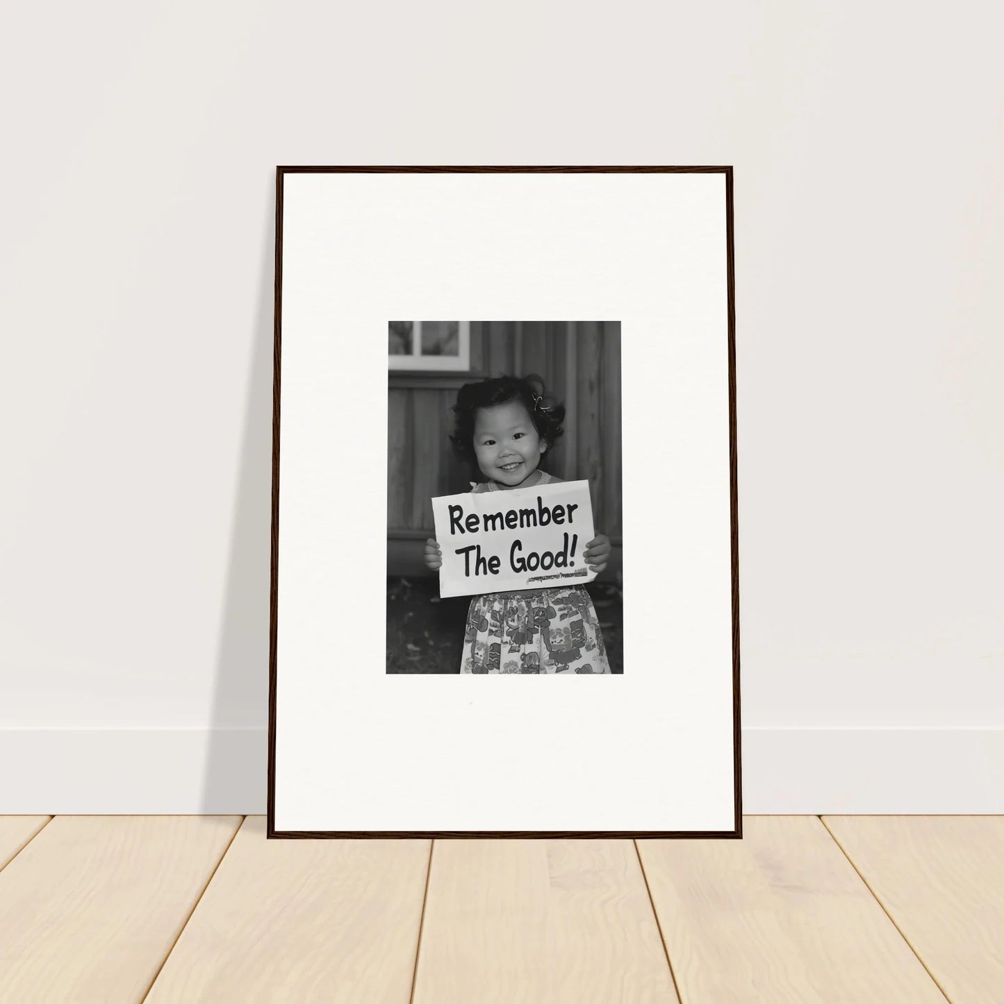 Framed black and white art of someone holding Remember The Good sign for Essence Savor Whispers