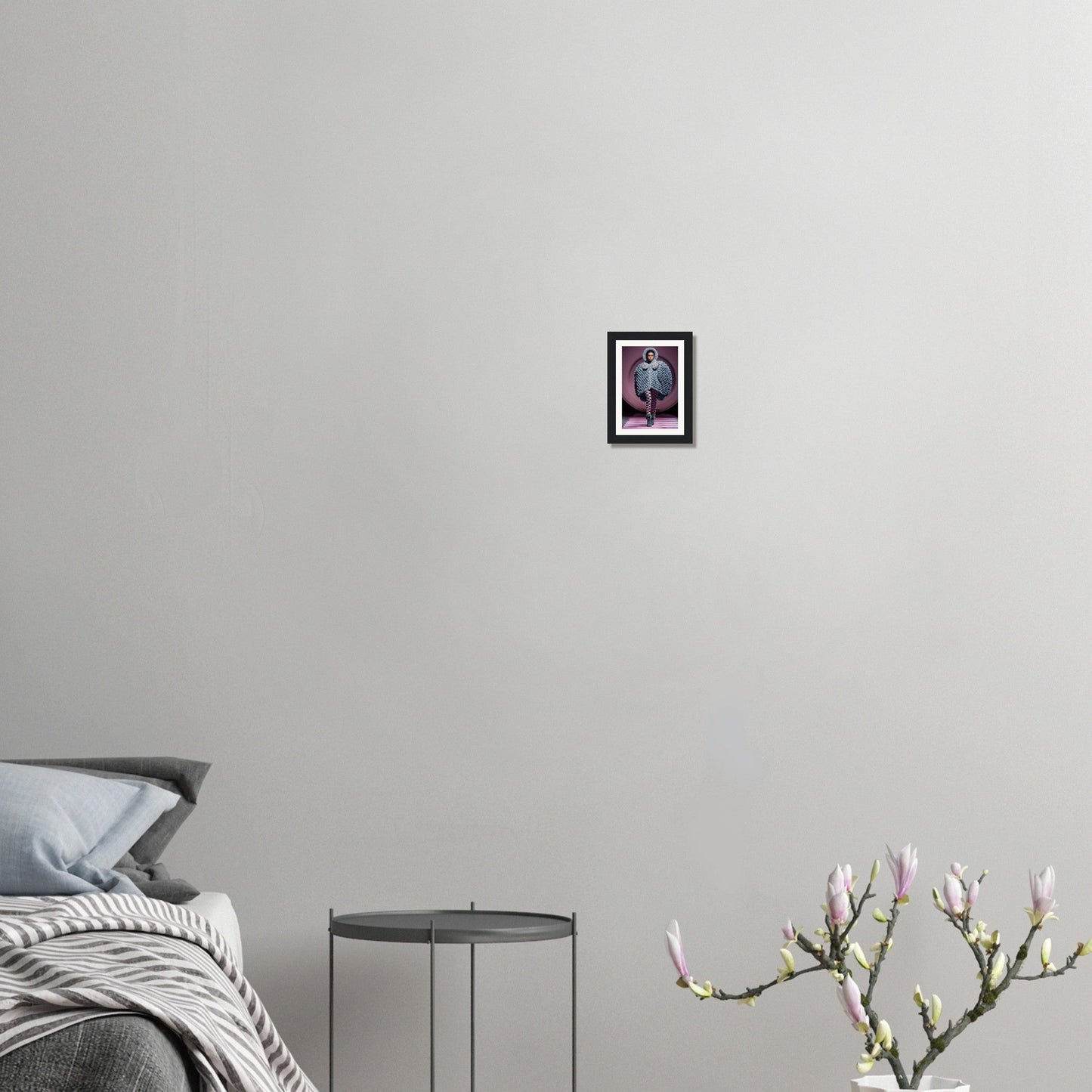 Minimalist bedroom interior with a bed, side table, and small framed artwork on the wall.
