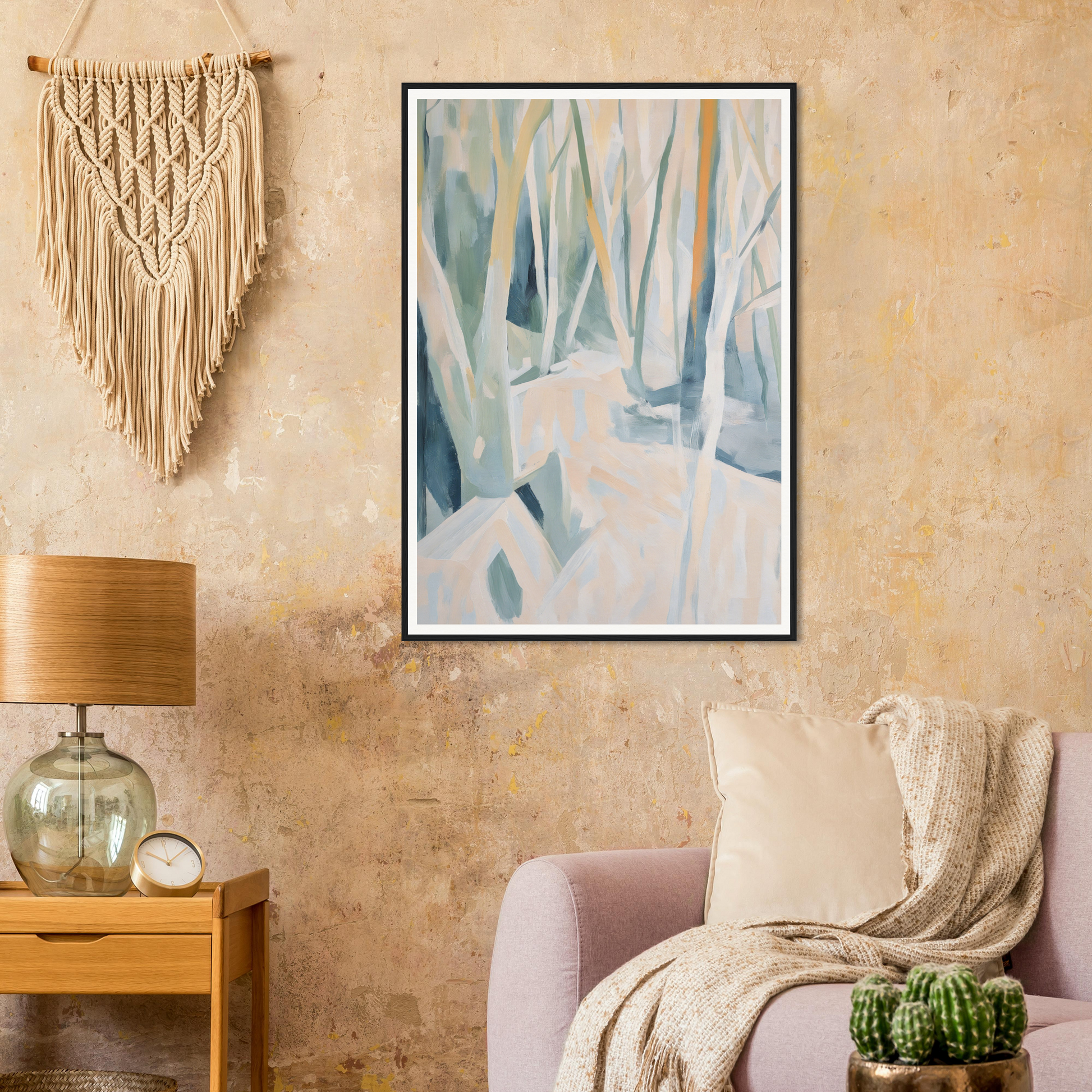 Framed wall art enhances the room decor above the couch, alongside a table lamp, macramé, and cactus.