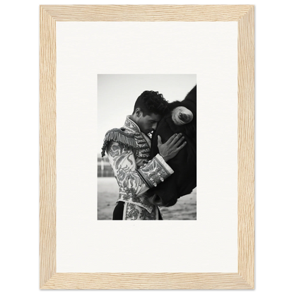 Black and white photo of a matador embracing a bull in a light wooden frame, Triumphant Shadows Embrace