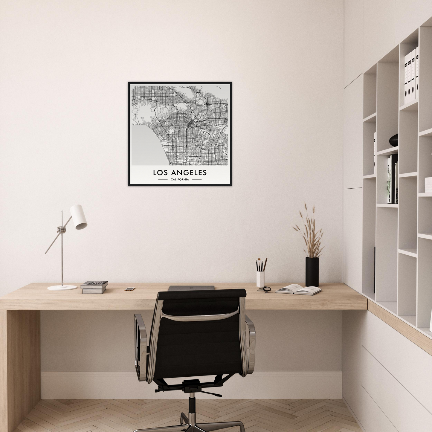 Minimalist home office workspace with a wooden desk, black office chair, and framed Los Angeles map on the wall.