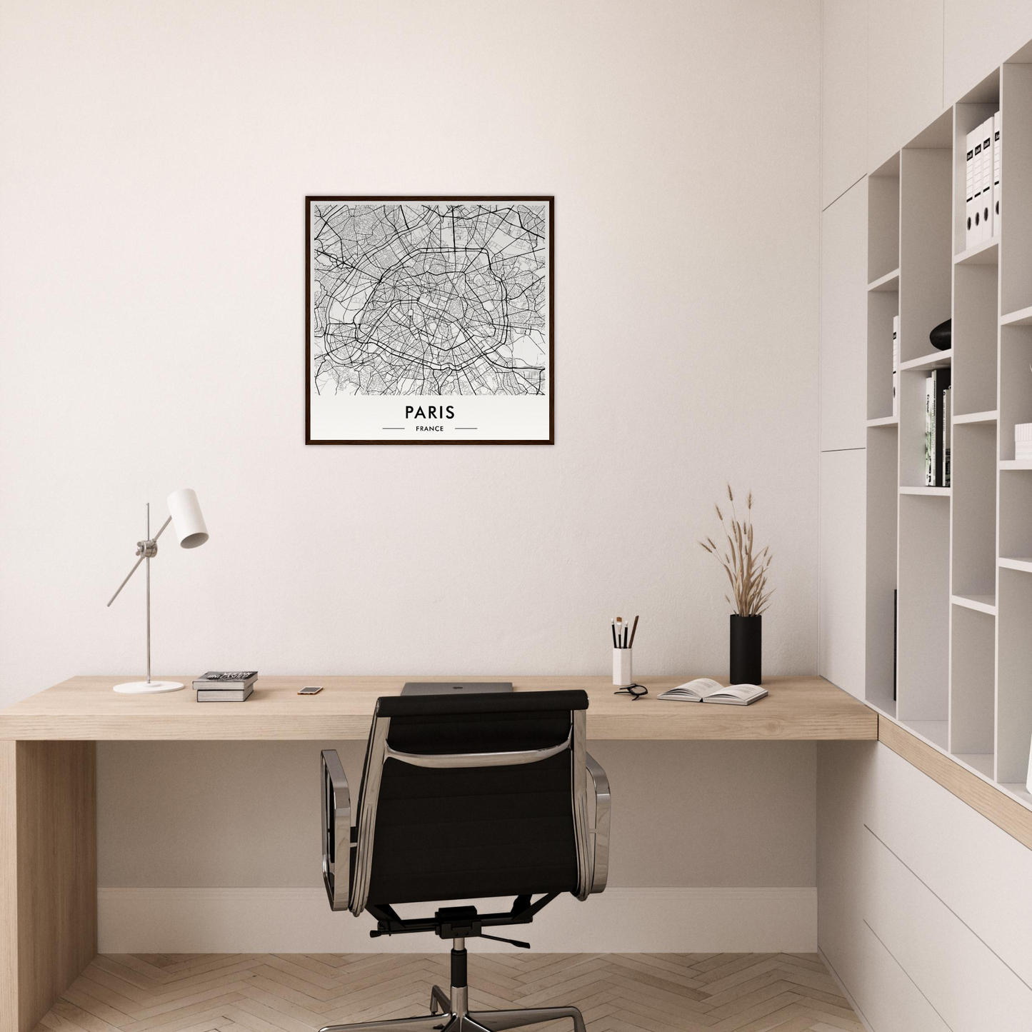 Minimalist home office workspace with a wooden desk, black office chair, and framed Paris map on the wall.