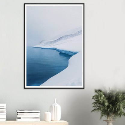 Framed wall art of a snowy landscape with a calm blue body of water.