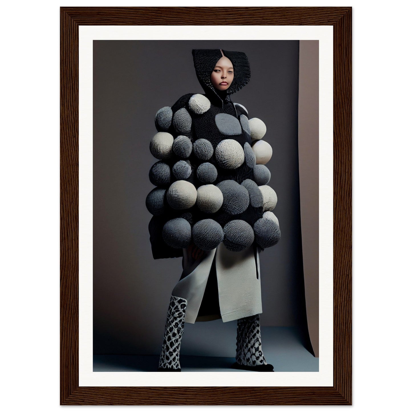 Avant-garde coat adorned with oversized spherical pom-poms in shades of gray and white.