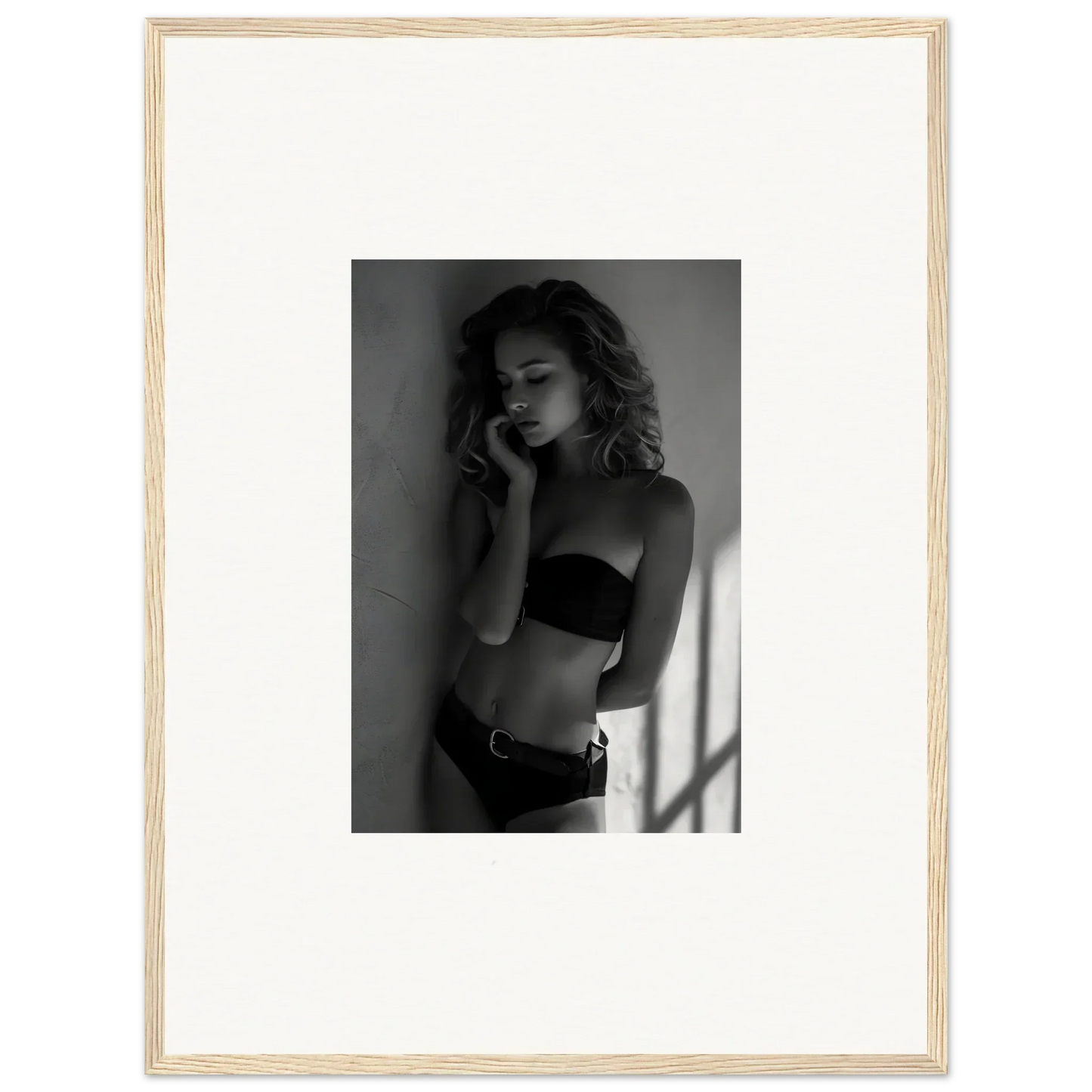 Black and white photograph of a woman in lingerie posing against a wall.