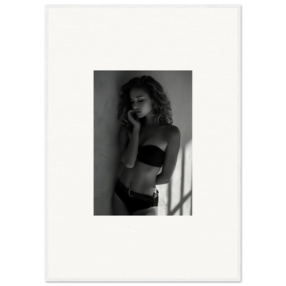 Black and white photograph of a woman in lingerie posing against a wall.