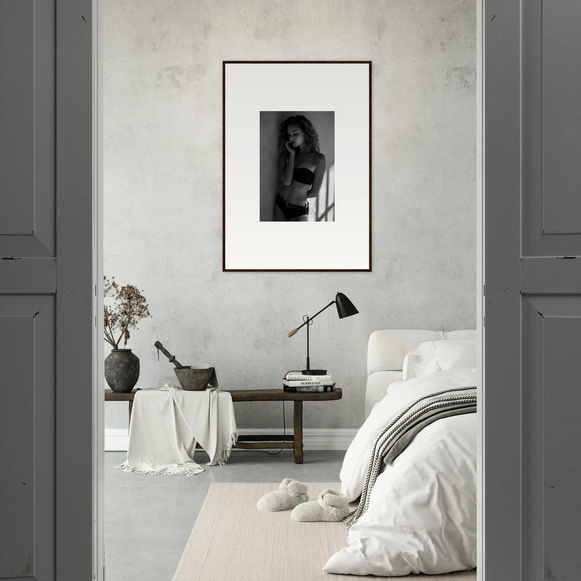 Framed black and white photograph of a person in a minimalist bedroom setting.