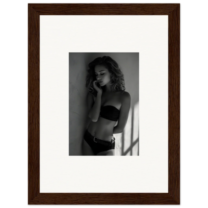 Black and white photograph of a woman in lingerie posing against a wall.