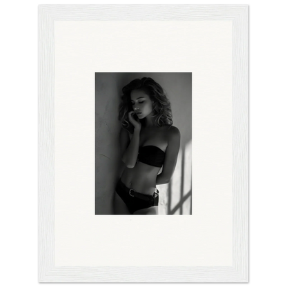 Black and white photograph of a woman in lingerie posing against a wall.