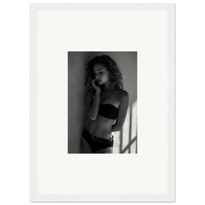 Black and white photograph of a woman in lingerie posing against a wall.