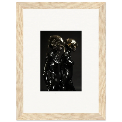 Framed photograph of two shiny, dark figures standing close together.