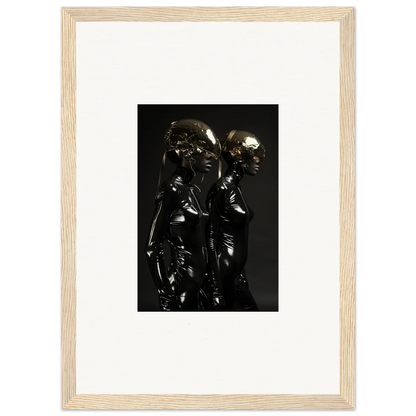 Framed photograph of two shiny black figures standing close together.