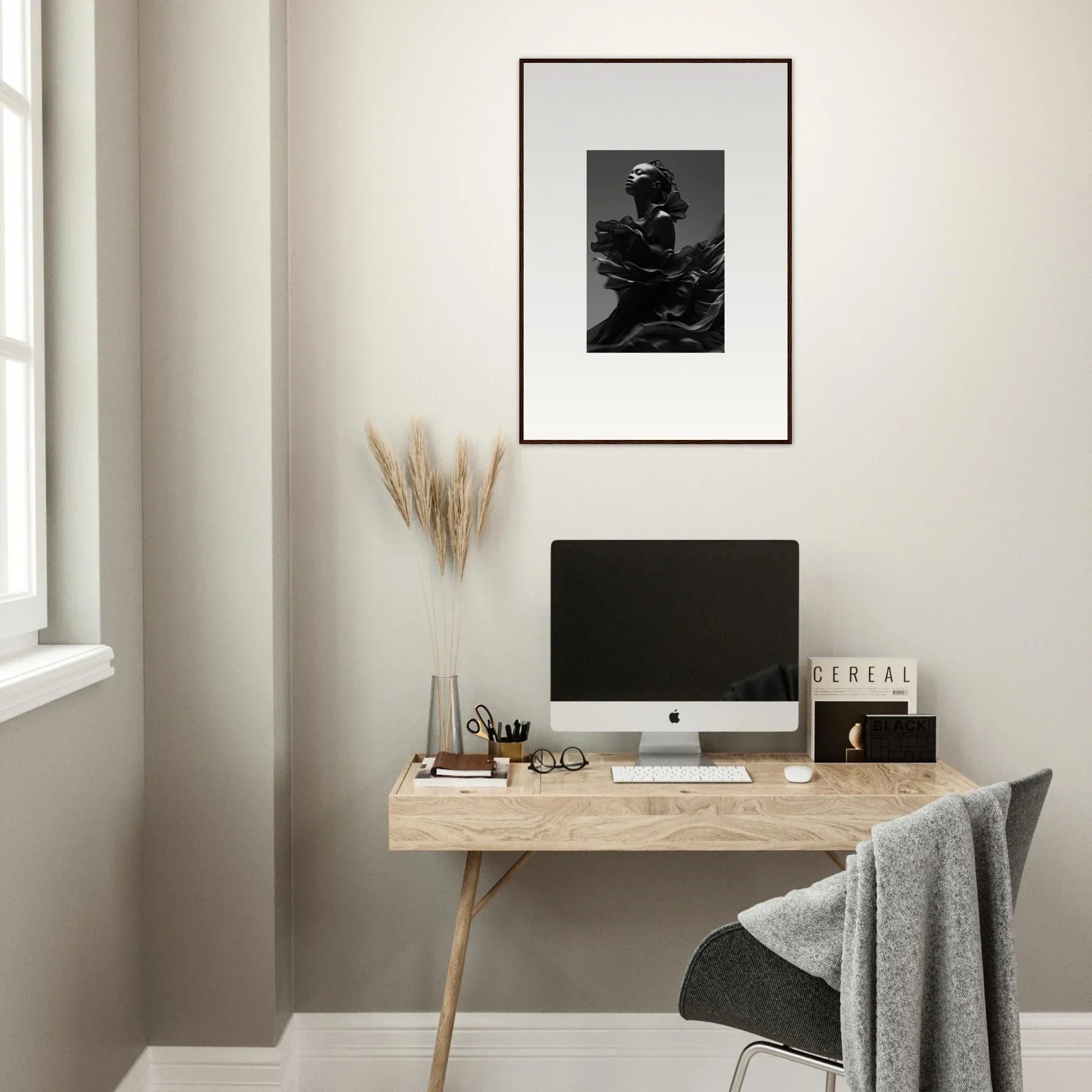 Minimalist home office workspace with a wooden desk, computer, and framed artwork.