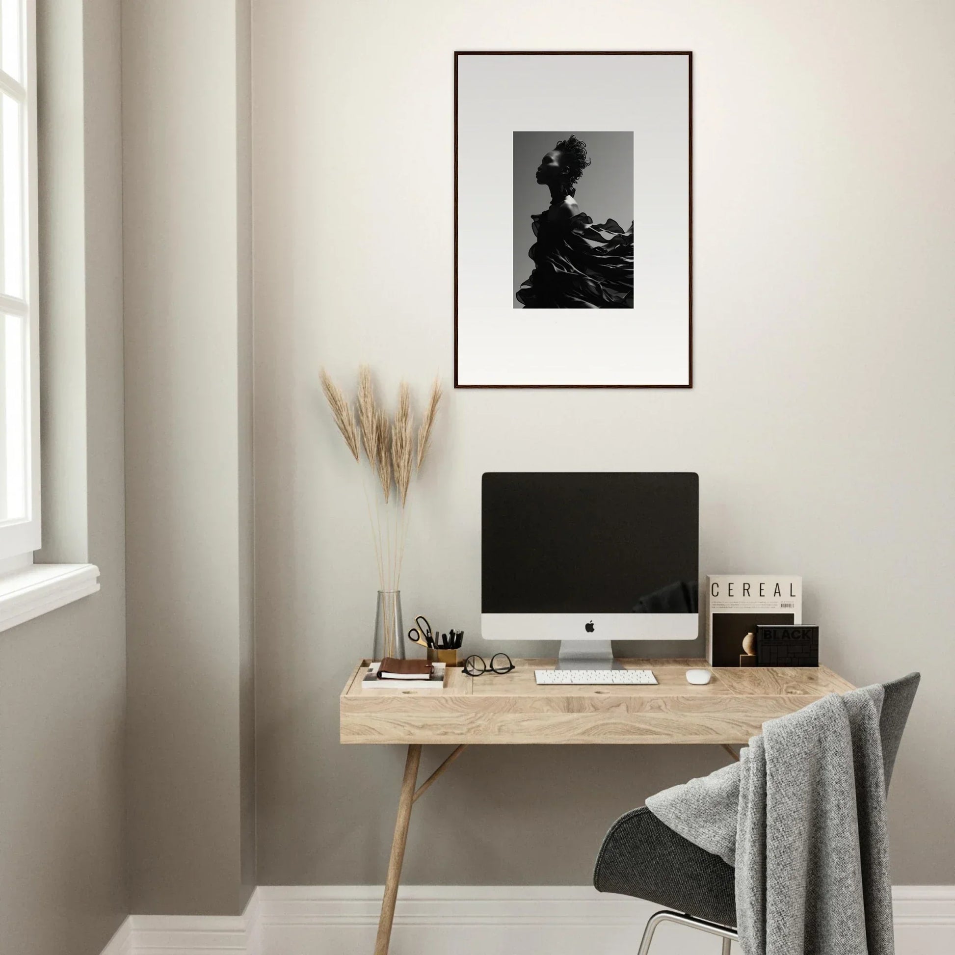 Minimalist home office workspace with a wooden desk, computer, and framed artwork.