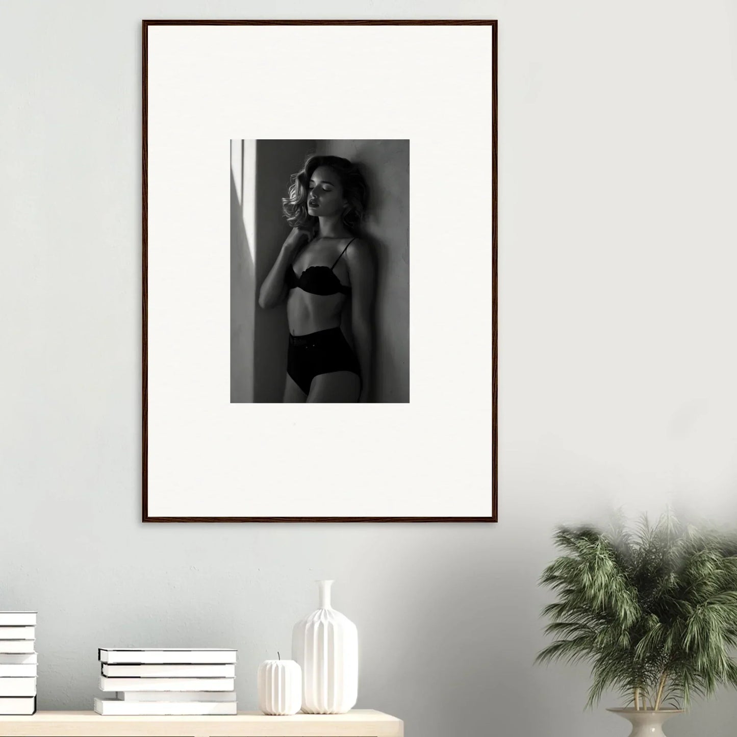 Framed black and white photograph of a woman in lingerie posing against a wall.