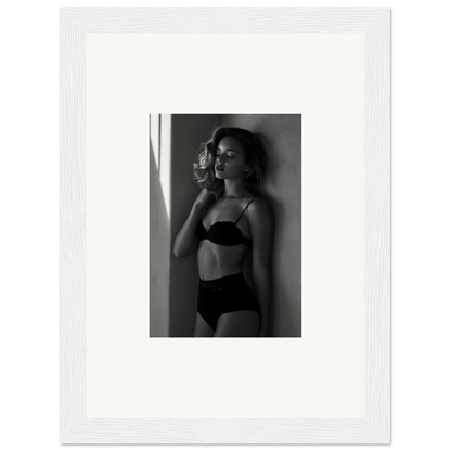 Black and white photograph of a woman in lingerie posing against a wall.