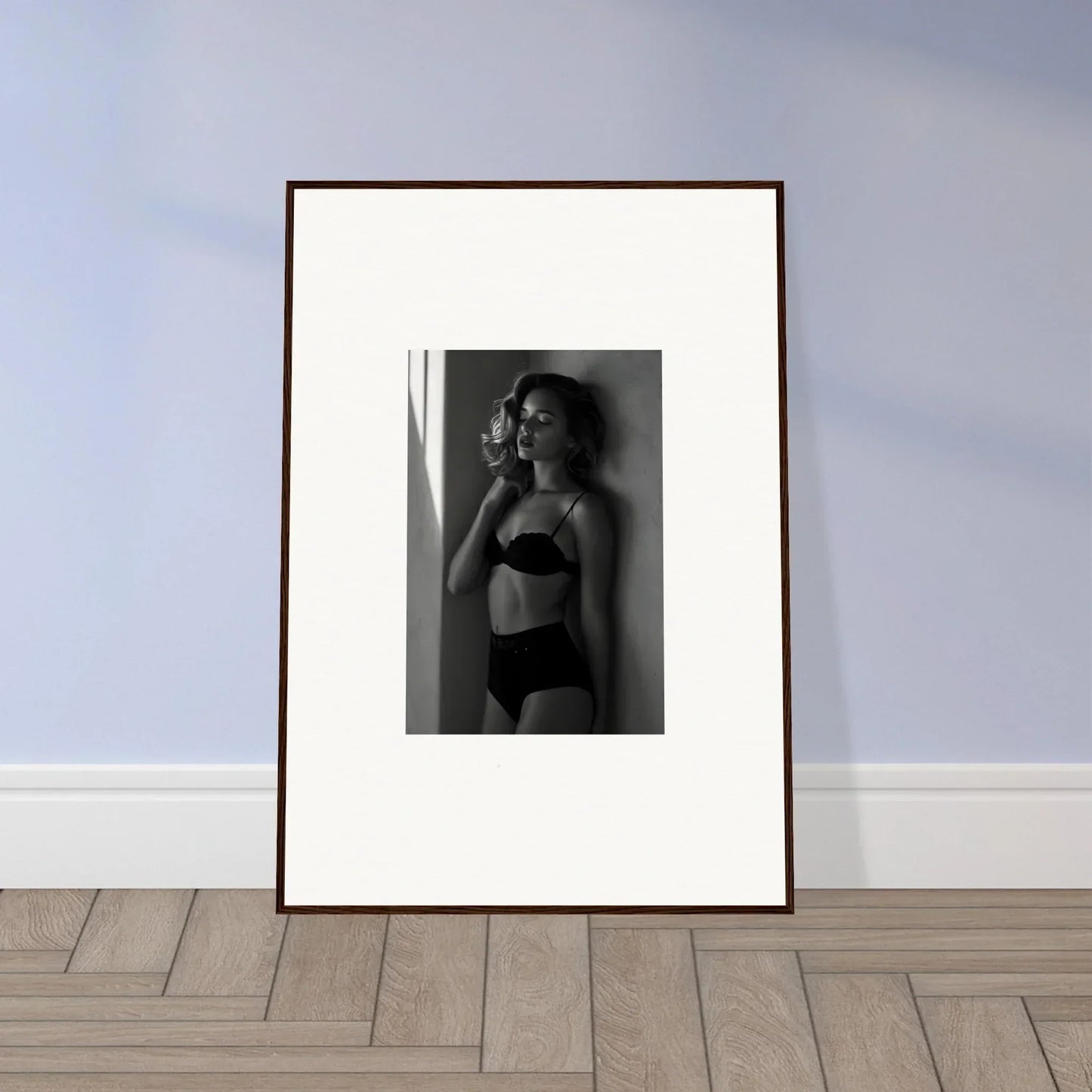 Framed black and white photograph of a woman in lingerie posing against a wall.